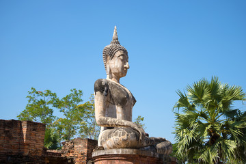 Obraz premium A view of the ancient sculpture of a sitting Buddha on the ruins of the Buddhist temple of Wat Mae Chon on a sunny afternoon. Sukhothai, Thailand