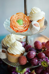 Close up shot of cake stand filled with cupcakes, fresh fruit and hand made sweets. Dark shadows, window light, grain, shallow depth of field.