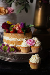Naked wedding cake and vanilla cupcakes - close up shot of wedding sweet table inspired by Dutch masters still lifes. Dark shadows, window light, grain.