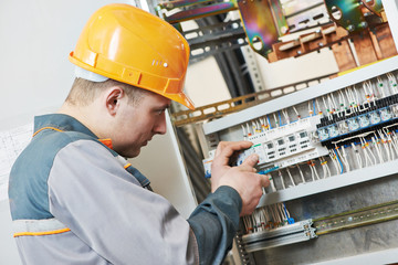 electrician works with electric meter tester in fuse box