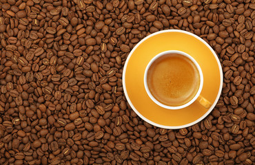 Espresso yellow cup and saucer on coffee beans
