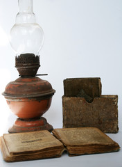 Fototapeta na wymiar An old kerosene lamp with a prayer book and worn books since the war