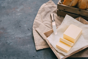 Pat of fresh farm butter  with a knife and bread over rustic background