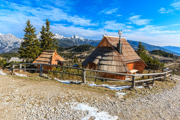 Cottages on Zeleni rob on Velika planina in spring with Kamnik-Savinja Alps in the background,...