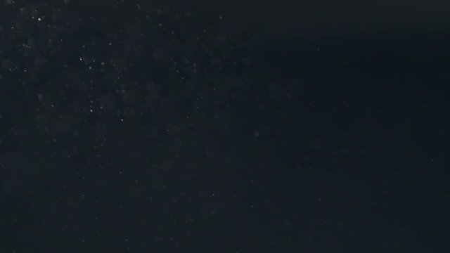 Slow motion of dust particles flow and float over black background, 180fps prores footage