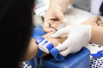 Nurse collecting blood samples from patient for analysis on the annual health,( focus on syringe).