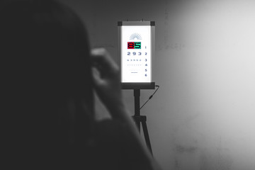 Woman reading the eye chart, the ophthalmologist is pointing at  numbers and examing the patient, eye care concept