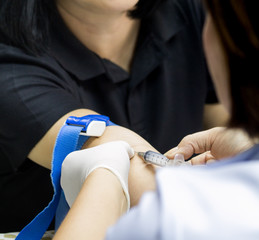 Nurse collecting blood samples from patient for analysis on the annual health,( focus on syringe).