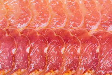 Dried ham lomo of pigs of the Pata Negra. Spanish dishes. Thin pieces of marble meat from above. Background food red color