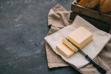 Pat of fresh farm butter  with a knife and bread over rustic background - 146345810