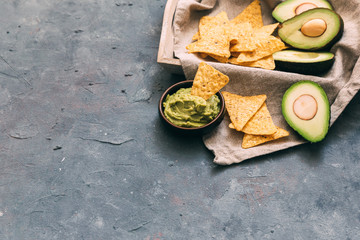 Traditional latinamerican mexican sauce guacamole in bowl and cut half avocado on vintage background. Top view. Copy space