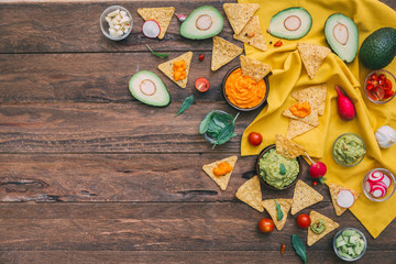 Mexican corn chips on wooden background, fresh guacamole sauce. Copy space. Top view