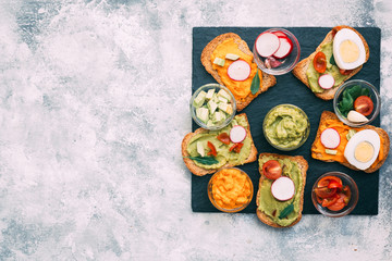 Traditional latinamerican mexican sauce guacamole with ingredients on dark background. Top view