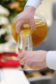 The waiter pours the juice into a glass at a festive buffet table