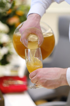 The waiter pours the juice into a glass at a festive buffet table