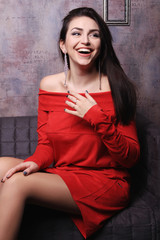 Beautiful brunette girl in red dress smiles.