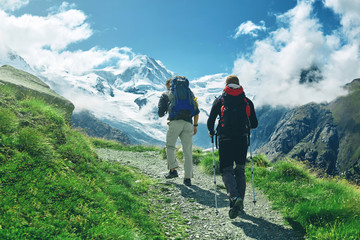 hikers with backpacks on the trail in the Apls, Swiss mountains. Trek near Matterhorn mount,...