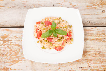 Risotto with tomato and pea on a wooden background 