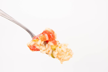 Risotto with tomato and pea on a fork on a white background