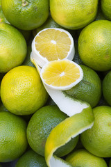 Fresh green Brazilian limes on display at an outdoor farmers market with decorative flourish 