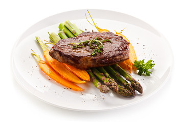 Grilled beefsteak with asparagus and carrot on white background