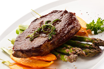 Grilled beefsteak with asparagus and carrot on white background