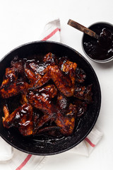 Chicken wings with sauce on white background with red striped towel. Summer barbeque concept.