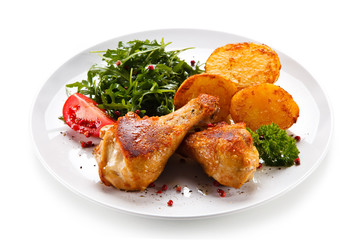 Roast chicken drumsticks with potatoes on white background