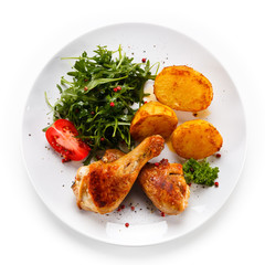Roast chicken drumsticks with potatoes on white background