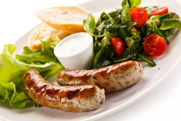Grilled sausages with vegetables on white background