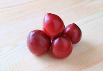 Piled Up Heart Shaped Ripe Gulf Ruby Plum Fruits on Wooden Table, Closed up 