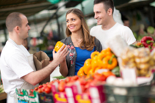 Couple buying from salesman at street market.