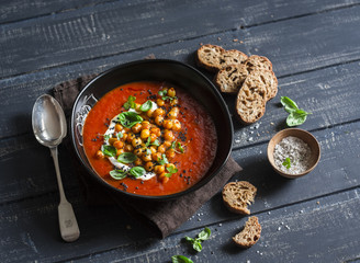 Tomato soup with spicy fried chickpeas on a dark wooden table, top view. Vegetarian food concept