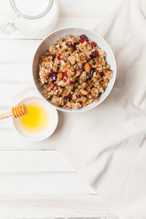 Morning granola with dried fruits, honey, milk and berries on white wooden background. Top view with copy space
