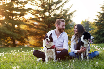 Beautiful couple cuddling and walking dogs outdoors