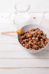 Morning granola with dried fruits, honey, milk and berries on white wooden background. Top view with copy space