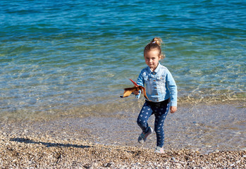 Little girl with a pterodactyl dinosaur toy on the beach © Alex Tihonov