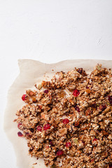 Baked granola with cranberry and honey on parchment sheet on white background. Morning concept with copy space