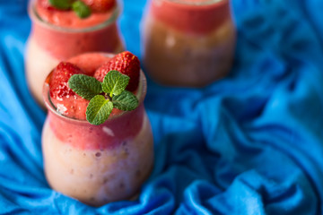 Fresh strawberry and banana smoothies decorated berry and mint leaves on blue napkin. Selective focus