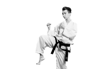 girl in karate suit kimono in studio at grey background. Female child shows judo or karate stans in...