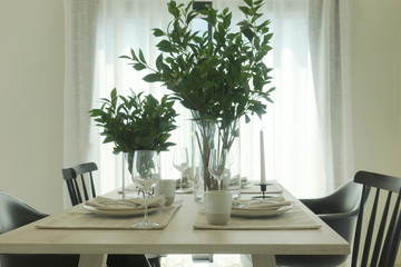 Simply dining table with vase of green leaves at the center