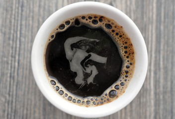 Mug of hot instant coffee on a wooden table with a spoon
