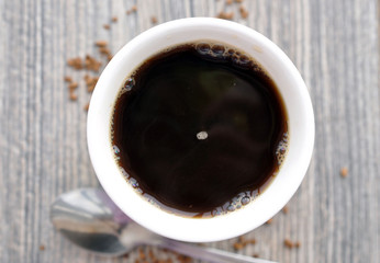 Mug of hot instant coffee on a wooden table with a spoon
