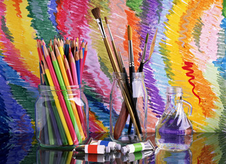 Obraz premium On a glass dark table are banks with colored pencils and brushes for drawing