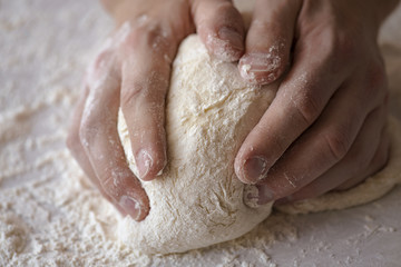 Fototapeta na wymiar Close-up male hands kneading dough on sprinkled with flour table