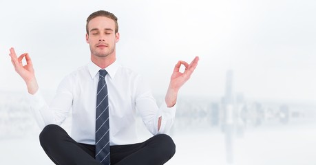 Business man meditating against blurry white skyline
