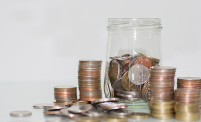 Glass jar saving money with coin on white background.