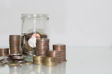 Glass jar saving money with coin on white background.