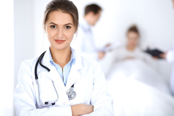 Female doctor smiling on the background with patient in the bed