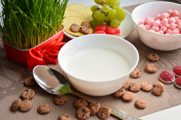 A plate of milk with a spoon, grapes and crispy balls for breakfast